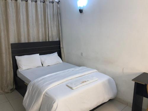 een kleine slaapkamer met een bed met witte lakens bij DBI GUEST HOUSE in Lagos