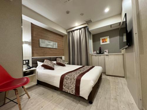 ein Hotelzimmer mit einem Bett und einem roten Stuhl in der Unterkunft Amand Hotel in Tokio