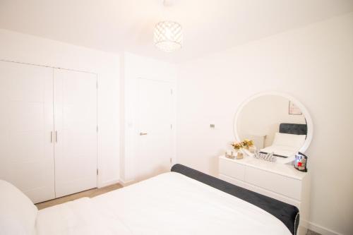 Habitación blanca con cama y espejo en Cosy 1Bedroom Apartment in Greenwich Cutty Sark, en Londres
