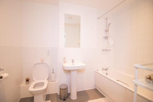 Baño blanco con aseo y lavamanos en Cosy 1Bedroom Apartment in Greenwich Cutty Sark, en Londres