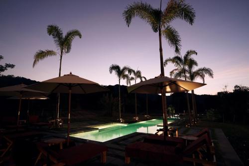 uma piscina com guarda-sóis e palmeiras à noite em Visama Mae Chan 