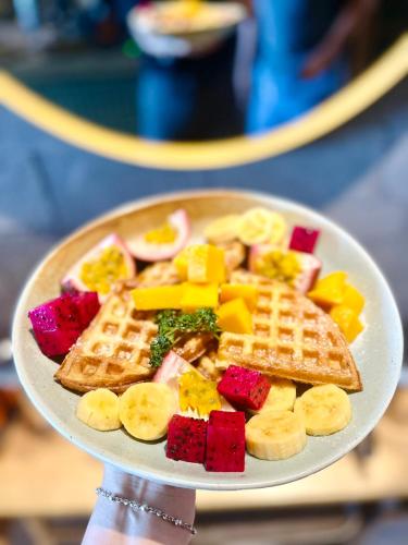 a plate of food with waffles and fruit on it at Paddy Boutique House Hoian in Hoi An