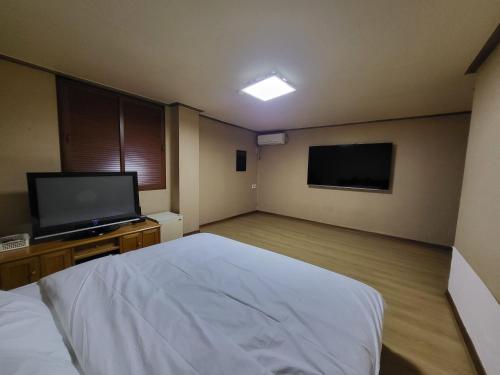 a bedroom with a bed and a flat screen tv at Mokhwa Motel in Icheon