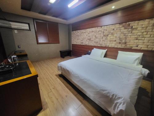 1 dormitorio con cama blanca y pared de ladrillo en Mokhwa Motel en Icheon