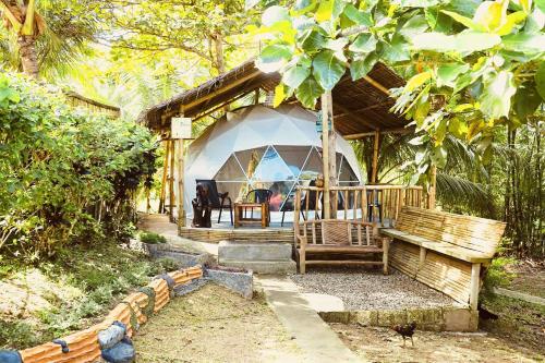 una casa con una tienda de campaña con una mesa y un banco en Eco Glamping Treehouses Closest Resort To All Tourist Attractions en Balilihan