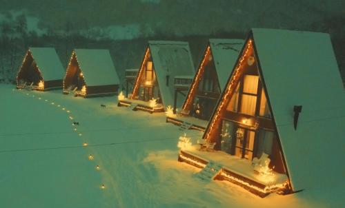 una fila de casas cubiertas de luces de Navidad en la nieve en WinterFell Mestia en Mestia