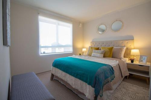 Un dormitorio con una cama grande y una ventana en casa con habitaciones disponibles, estacionamiento privado, patio y áreas comunes para compartir en Puerto Montt