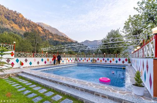 a swimming pool in a resort with mountains in the background at Zostel Plus Kareri in Dharamshala