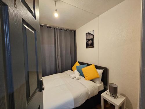 a small bedroom with a bed with yellow and blue pillows at Spitalfields Rooms in London