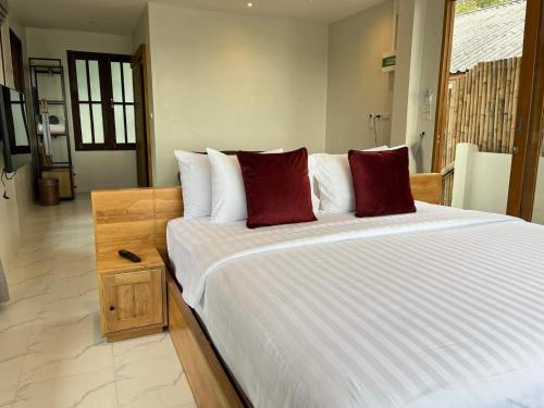een slaapkamer met een groot bed met rode kussens bij Benjamin's Hut in Srithanu
