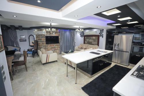 eine Küche und ein Wohnzimmer mit einem Tisch und Geräten in der Unterkunft Heliopolis Heights, 3-Bedroom Grandeur, Jacuzzi, 5 AC & 4 TVs in Kairo