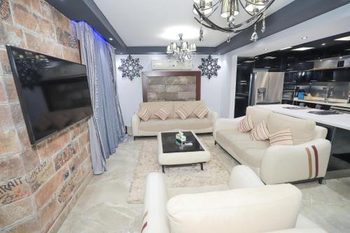 a living room with white couches and a brick wall at Heliopolis Heights, 3-Bedroom Grandeur, Jacuzzi, 5 AC & 4 TVs in Cairo