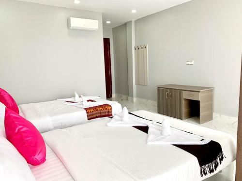 two beds in a hotel room with pink pillows at Sok Eng Hotel ( សណ្ឋាគារ សុខ អេង ) in Sihanoukville