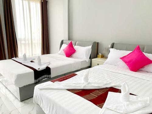 2 bedden met roze kussens in een kamer bij Sok Eng Hotel ( សណ្ឋាគារ សុខ អេង ) in Sihanoukville