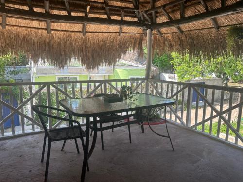 una mesa y sillas en un balcón con techo de paja en Punta Arena EcoHostal & EcoFit - Your Eco-Friendly Oasis, en Playa Punta Arena