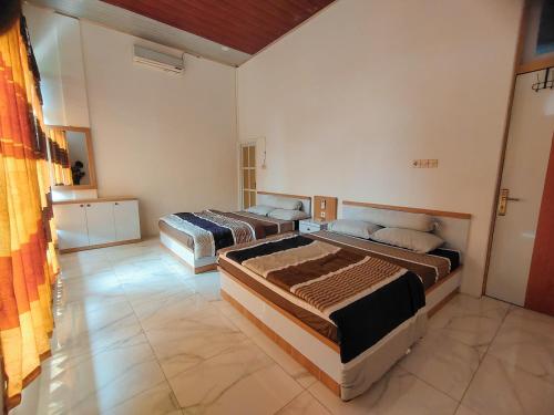 een slaapkamer met 2 bedden in een kamer bij Java Mulia Homestay 