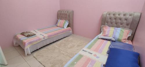 a childs bedroom with two beds and a rug at HOMESTAY KHALISH in Gua Musang