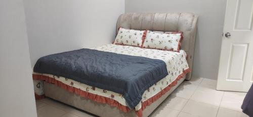 uma pequena cama num quarto com uma colcha e almofadas em HOMESTAY KHALISH em Gua Musang
