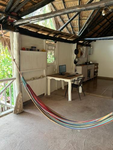 a hammock in a room with a table and a laptop at Punta Arena EcoHostal & EcoFit - Your Eco-Friendly Oasis 01 in Playa Punta Arena