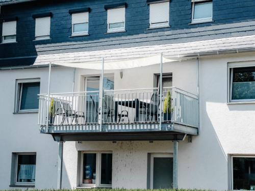 a white building with a balcony with tables and chairs at Timeout Royal in Ellar