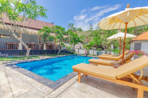 einen Pool mit 2 Stühlen und einem Sonnenschirm in der Unterkunft Kalpataru Cottage in Nusa Penida