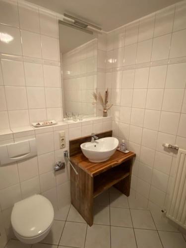 ein Badezimmer mit Waschbecken, Toilette und Spiegel in der Unterkunft Haus Strandeck Apartment Meeresrauschen 12 in Göhren