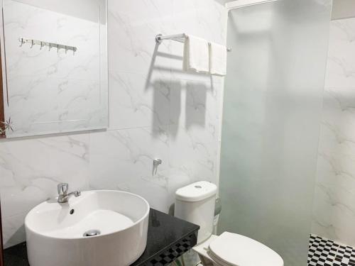 a white bathroom with a sink and a toilet at Sok Eng Hotel ( សណ្ឋាគារ សុខ អេង ) in Sihanoukville