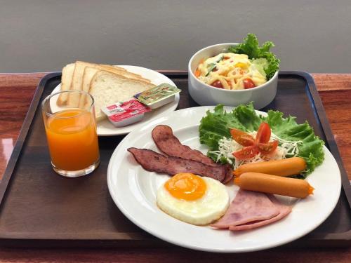 a tray with a plate of breakfast food and a glass of orange juice at Ratana Boutique Resort - Mae Phim in Ban Ang