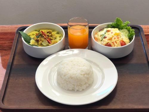 a tray with rice and bowls of food and a glass of orange juice at Ratana Boutique Resort - Mae Phim in Ban Ang