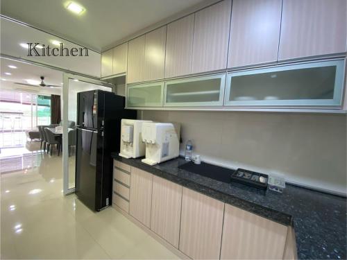 a kitchen with a black refrigerator and white cabinets at Sandakan Ijm pool view condo in Sandakan