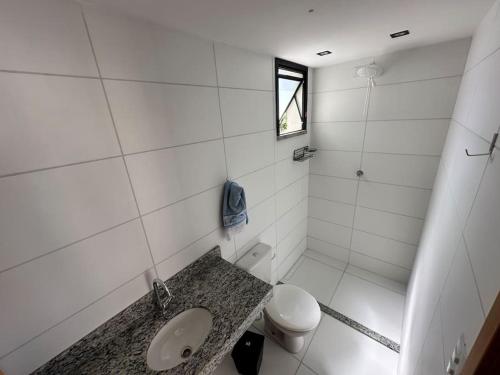 a white bathroom with a toilet and a sink at Apartamento Para Temporada in Ilhéus