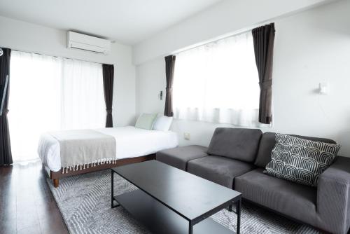 ein Wohnzimmer mit einem Sofa und einem Bett in der Unterkunft BREAKY HOTEL west coast in Urazoe