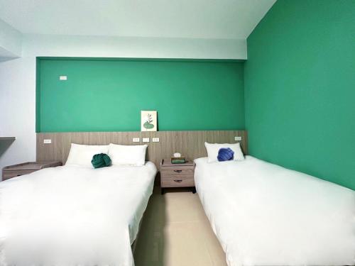 two beds in a room with a green wall at NuNc in Kenting