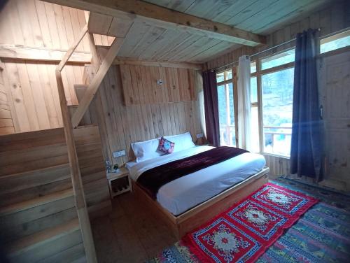 a bedroom with a bed in a wooden house at Alpine Homestay at Gadagusain in Banjār