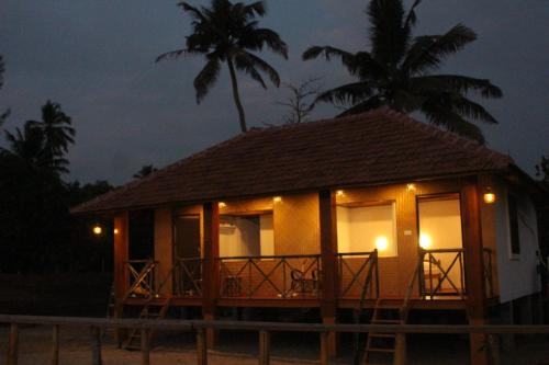 a small house with a deck at night at Marari Sunset Beach Villa in Alleppey