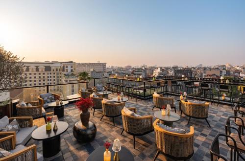 Blick auf eine Terrasse mit Tischen und Stühlen in der Unterkunft GRAND HOTEL du LAC Hanoi in Hanoi