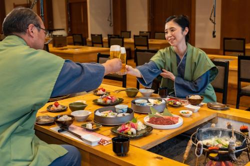 a man and a woman sitting at a table with food at KAMENOI HOTEL Nikko Yunishigawa in Nikko