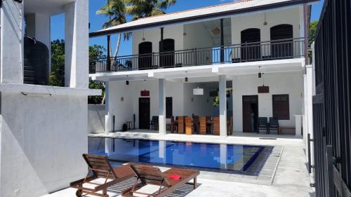 a house with a swimming pool and two chairs at Ahangama Eco Villa in Ahangama