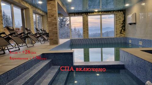 a swimming pool with chairs in a building with a mountain view at SPA Resort Villa Sofia in Yablunytsya