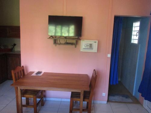 a dining room with a table and a television on a wall at Residence Kathyly in Diego Suarez