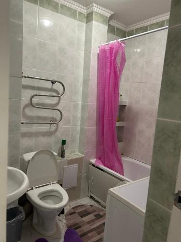ein Bad mit einem WC und einem rosa Duschvorhang in der Unterkunft Апартаменты в центре Астаны in Astana