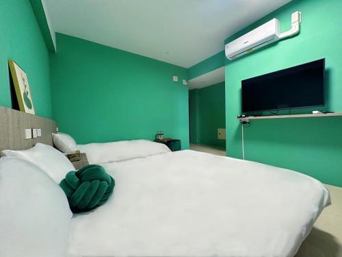 a bedroom with a large white bed with a green wall at NuNc in Kenting