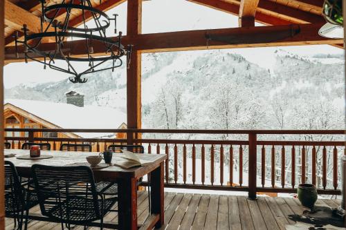 a table and chairs on a deck with a view of snow covered mountains at Joubarbe Rose By Lodji in Saint-Martin-de-Belleville