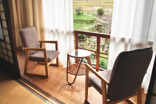 uma varanda com 2 cadeiras, uma mesa e uma janela em すさのわ em Izumo