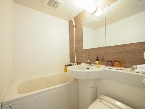 a white bathroom with a sink and a toilet at Tabino Hotel Kashima in Kamisu