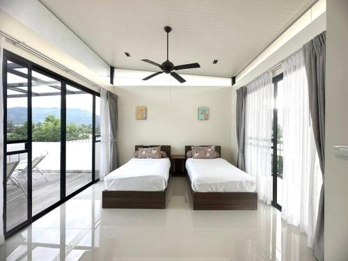 a bedroom with two beds and a ceiling fan at Friendly Townhouse Laguna Park in Thalang