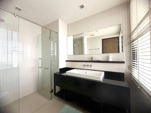 La salle de bains est pourvue d'un lavabo, d'un miroir et d'une douche. dans l'établissement Friendly Townhouse Laguna Park, à Thalang
