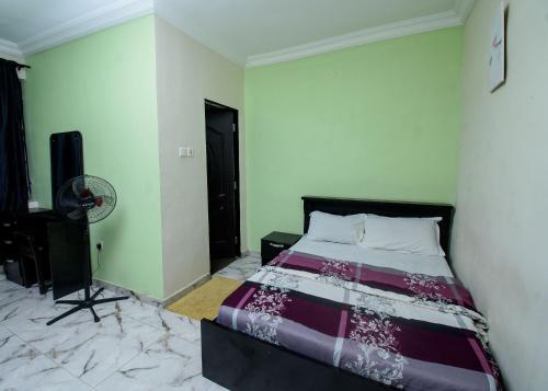 a bedroom with a bed and a fan at D'Tavern Apartment in Ibadan
