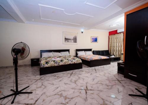 a bedroom with a bed and a couch and a fan at D'Tavern Apartment in Ibadan