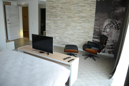 a bedroom with a tv and two chairs at Hotel Nar in Trebinje